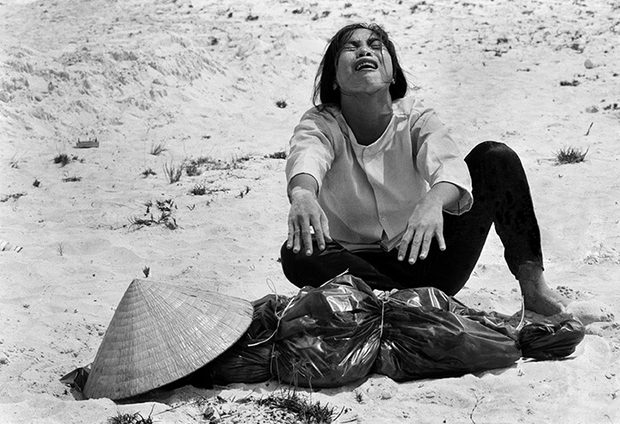 A woman mourns over the body of her husband after identifying him by his teeth, and covering his head with her conical hat.