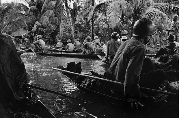 Caught in a sudden monsoon rain, part of a company of about 130 South Vietnamese soldiers moves downriver in sampans during a dawn attack on a Viet Cong camp, January 10, 1966.