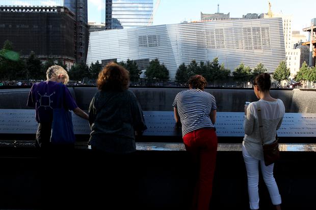 Families crowd around the South Pool at the World Trade Center Memorial plaza with the still incomplete 9/11 Museum in the background. Families crowd around the South Pool at the World Trade Center Memorial plaza.