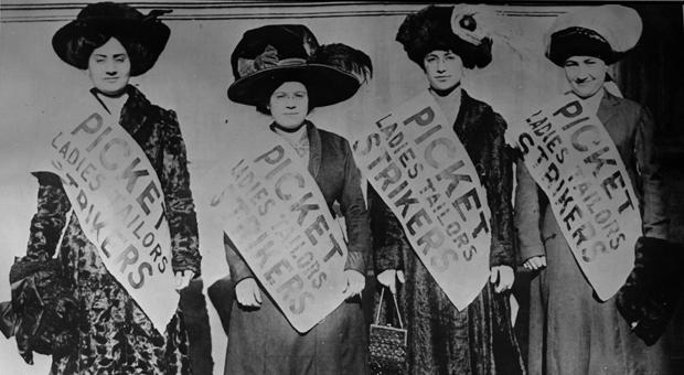 Four women strikers wear signs that say “Picket, Ladies Tailors Strikers” as they march in the cold streets. The smallest garment shops could not withstand the idle period and negotiated concessions w