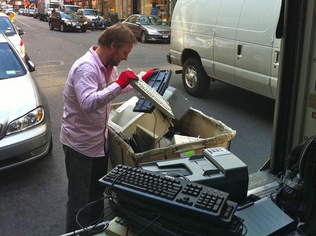 John Kirsch picks keyboards out of a bin of e-waste to weigh and load onto his truck.
