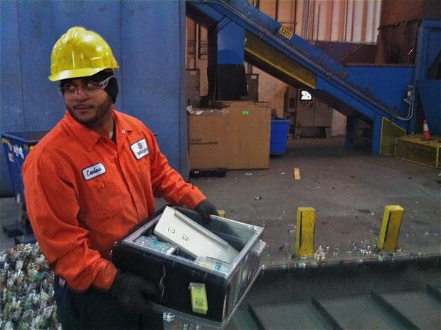 We Recycle! supervisor Carlos Jorge prepares to drop the Gateway computer on a conveyor belt leading into a large shredder.