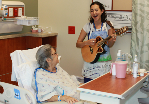 Danielle DeCosmo, an artist in residence at Shands, plays for a patient.