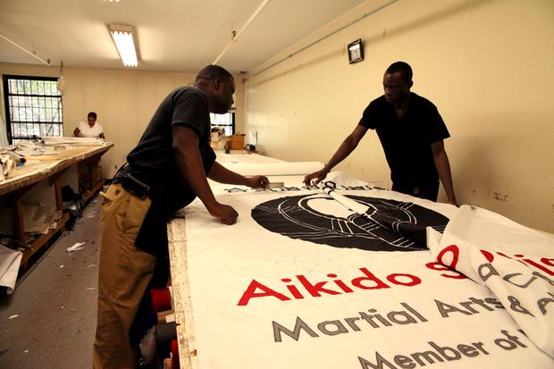 Ebrima Camara and a coworker put the finishing touches on a large banner.