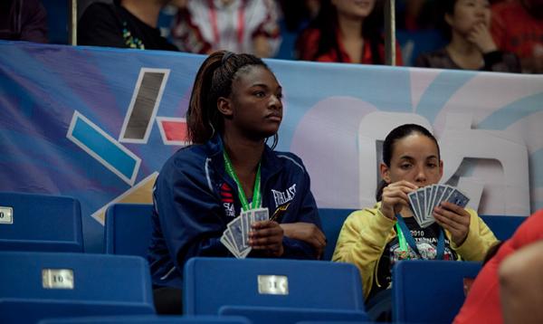 Claressa Shields and Alex Love play cards in the crowd waiting for their teammates to compete.