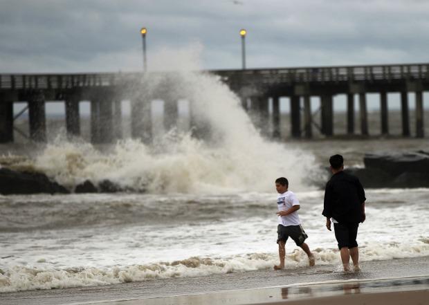 People walk along a sand-swept beach at Coney Island following heavy rain and winds from Hurricane Irene on August 28, 2011 in the Brooklyn borough of New York City. People walk along a sand-swept beach at Coney Island following heavy rain and winds from Hurricane Irene on August 28, 2011 in the Brooklyn borough of New York City.