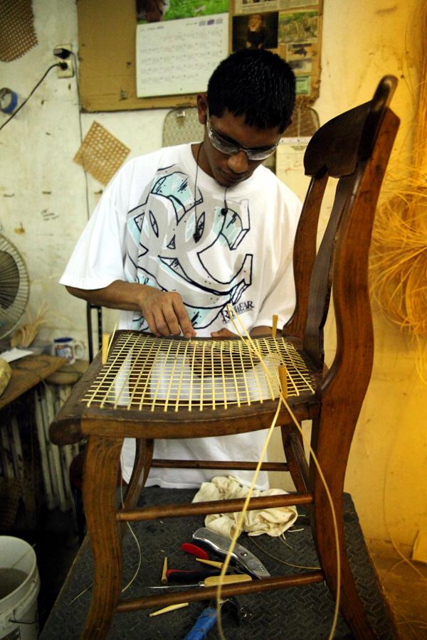 Eric Aguilar canes a chair.