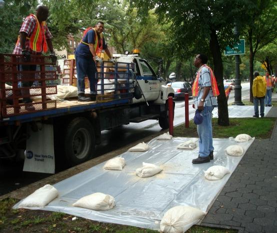 MTA workers covered subway grates with plastic sheets held down by sandbags along Eastern Parkway in Crown Heights, Brooklyn. MTA workers covered subway grates with plastic sheets held down by sandbags along Eastern Parkway in Crown Heights, Brooklyn.