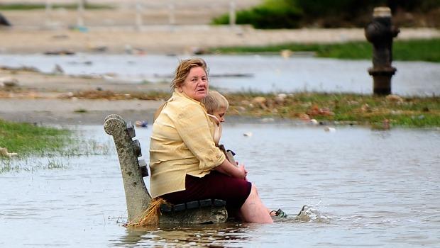 A woman and a child sit on a public bench amid floodwater on Rockway Beach after Hurricane Irene swept through New York City on August 28, 2011. A woman and a child sit on a public bench amid floodwater on Rockway Beach after Hurricane Irene swept through New York City on August 28, 2011.