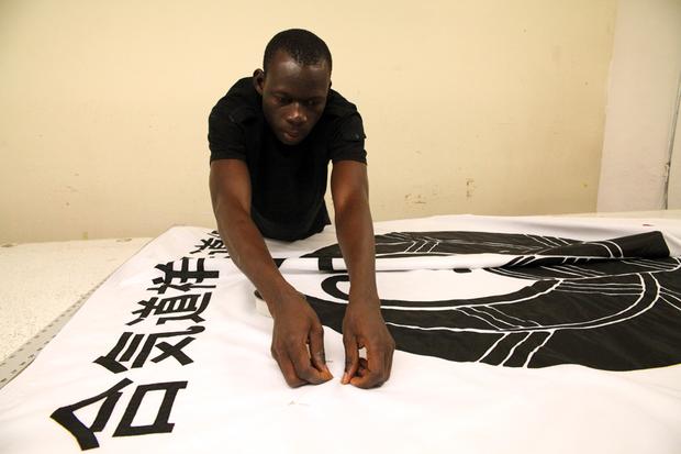 A tailor from Burkina Faso works on a banner.