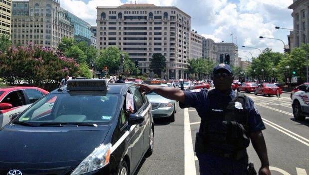 A police officer surrounded by D.C. taxicabs tries to deal with gridlock outside of the Wilson Building.