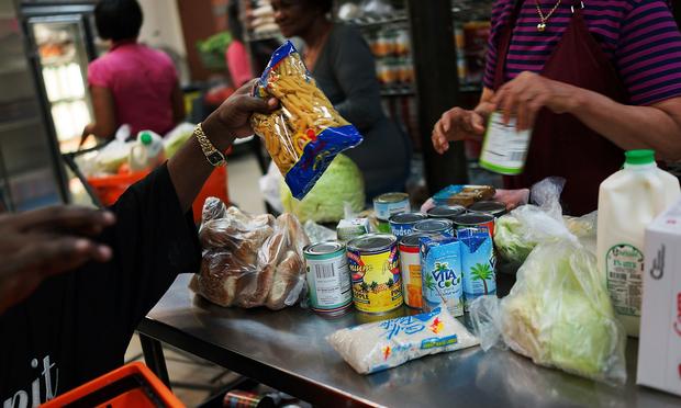 A client of the West Side Campaign Against Hunger food pantry fills up a box with food on July 24, 2013 in New York City. The food pantry assists thousands of qualifying New York residents.