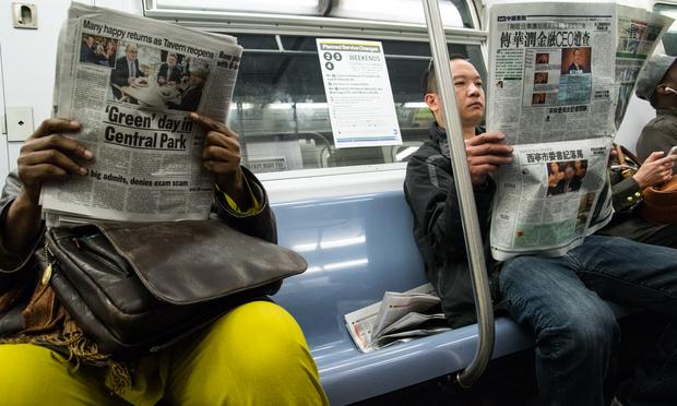 Passengers read newspapers in English and Chinese on the subway in Manhattan. Passengers read newspapers in English and Chinese on the subway in Manhattan.