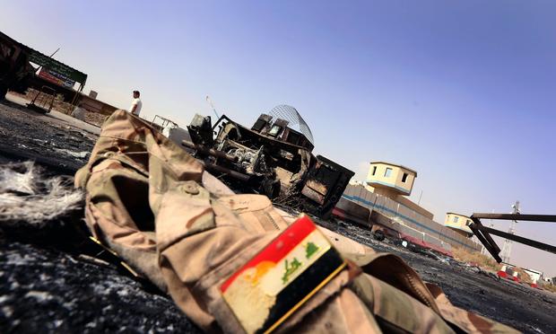 The jacket belonging to an Iraqi Army uniform lies on the ground in front of the remains of a burnt out Iraqi army vehicle some 10km of east of the northern city of Mosul, on June 11, 2014.