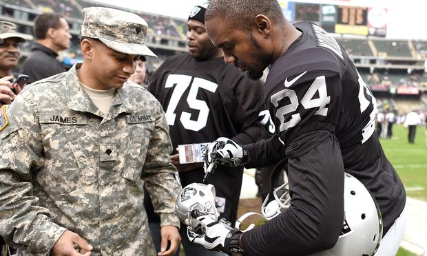 Charles Woodson #24 of the Oakland Raiders signs an autograph for a member of the U.S. Army prior to playing the San Francisco 49ers at O.co Coliseum on December 7, 2014