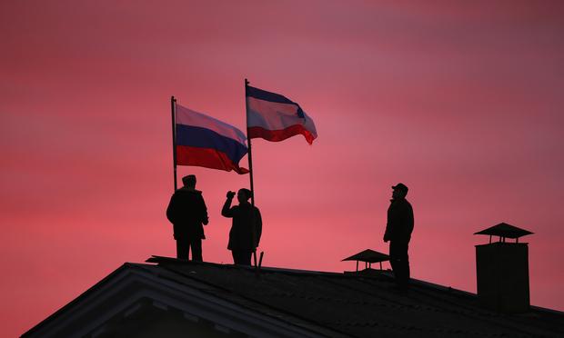 Cossack men install a Russian flag and a Crimean flag on the roof of the City Hall building on March 17, 2014 in Bakhchysarai, Ukraine.