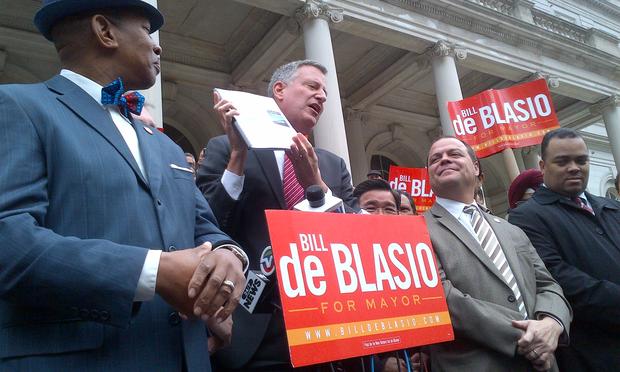 Bill de Blasio holds up his policy book at a rally for comprehensive immigration reform the day after the second mayoral debate.