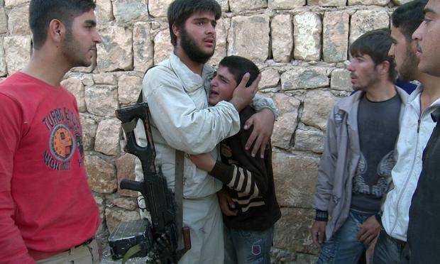 A young boy is consoled after his grandparents appear to have been killed in a government strike on the Sunni village of Al Barra. Syria