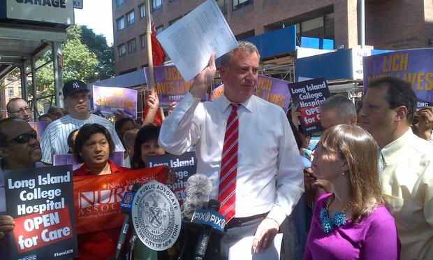 Bill de Blasio holds up the court order that resumed ambulance service to Long Island College Hospital