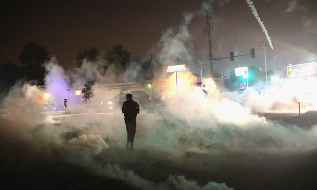 A person runs through a clowd of tear gas that police launched at demonstrators protesting the killing of teenager Michael Brown on August 17, 2014 in Ferguson, Missouri.