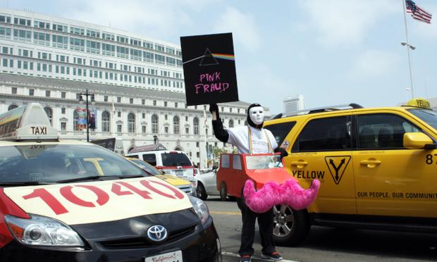 A protester mocks ride service Lyft and its signature pink mustaches at a July cab driver rally outside San Francisco City Hall.