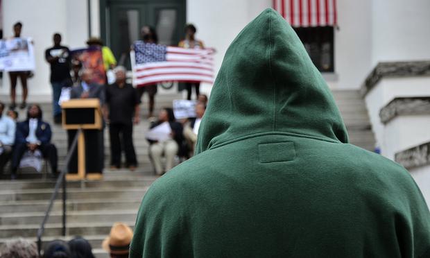 A man with hoodie watches the speakers on the steps of the Capitol Building in Tallahassee, Florida at a Rally March for Trayvon Martin.