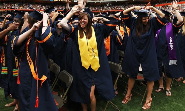 Graduates high-five at the 2012 Syracuse University commencement. Economists tell us that degrees lead to higher pay and a happier life, but how does college actually produce those gains? Graduates at ceremony