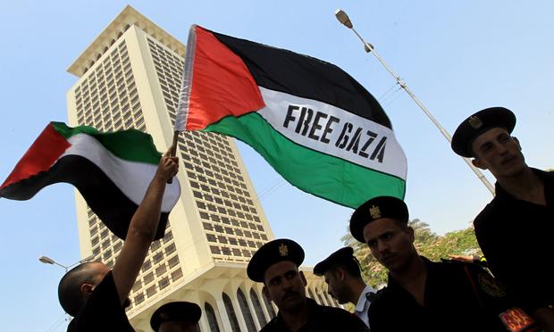 Egyptian protesters wave Palestinian flags with a Free Gaza slogan as they face riot police during a demonstration in front of Foreign Ministry headquarters in Cairo on May 31, 2010.