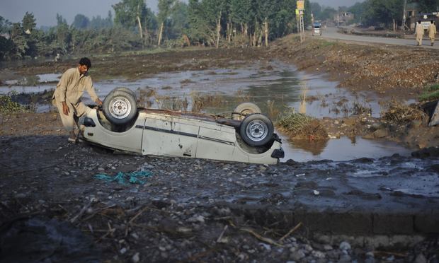 A Pakistani flood survivor inspects an overturned car in Charsadda on August 4, 2010. Devastating floods have swept away farmland and devastated livestock in Pakistan's northwest.