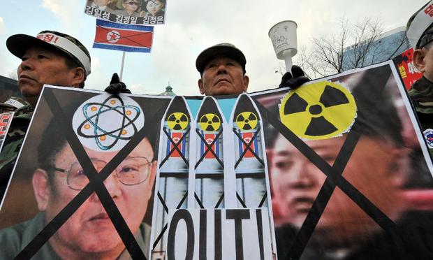 A South Korean veteran holds a placard showing North Korean flags and portraits of Kim Jong-Il (L) and his son Jong-Un (R) during a rally in Seoul on December 2, 2010