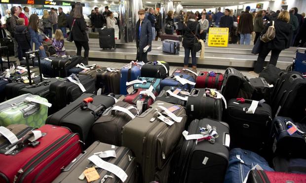 Unclaimed bags in the foreground as travelers retrieve their luggage at New York's LaGuardia Airport on December 28, 2010.