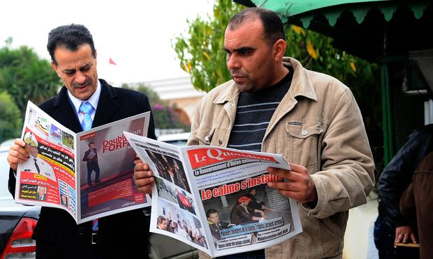 Tunisian men read the newspaper on Janaury 18, 2011 at the Kasbah in Tunis.