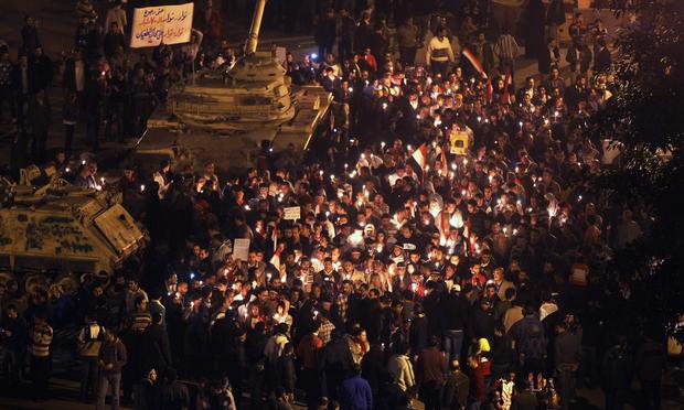 Anti-government protesters walk past Egyptian Army tanks during a candlelight vigil for those killed during the uprising in Tahrir Square on February 9, 2011 in Cairo, Egypt.