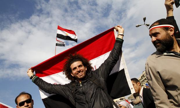 Egyptian anti-government demonstrators hold their national flag as they gather at Cairo's Tahrir Square on February 10, 2011.
