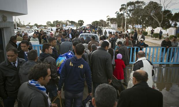 Tunisians working and living in Libya arrive on February 22, 2011 at the Ras Jdir border post (in the background), near the Tunisian city of Ben Guerdane after they fled Libya.