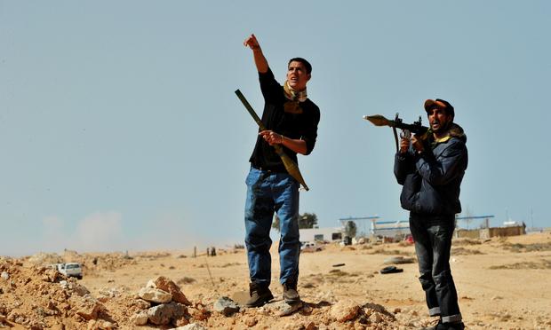 Libyan rebel fighters hold a rocket propelled grenade launcher (RPG) as a pro Kadhafi fighter jet fly over the eastern oil port city of Ras Lanuf on March 11, 2011.