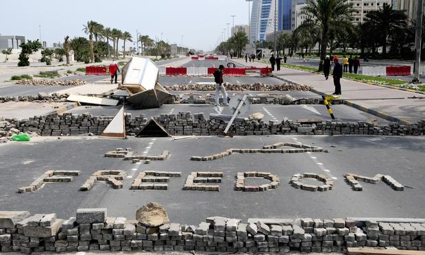 Bahraini anti-government protesters stand close to makeshift roadblocks in Manama on March 14, 2011, a day after Bahraini police clashed with demonstrators trying to occupy Manama's banking centre.
