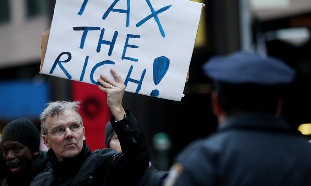 A protester holds a 'Tax the Rich' sign as he marches during a rally against budget slashing held by union supporters on March 24, 2011 in New York City