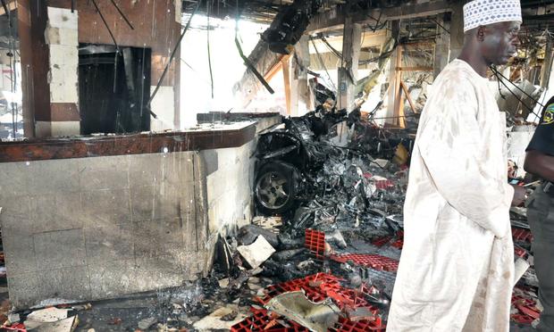 A man stands next to debris after a suicide bombing in Abuja, Nigeria.