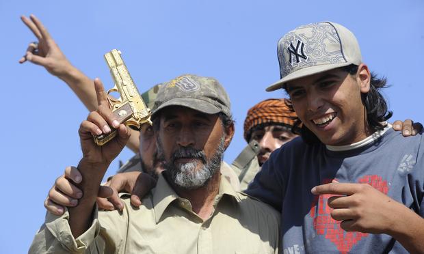 Libyan National Transitional Council (NTC) fighters hold what they claim to be the gold-plated gun of ousted Libyan leader Moamer Kadhafi