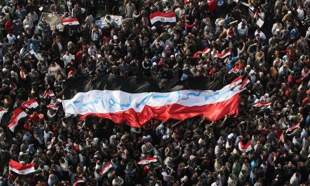 Egyptian demonstrators hold up a huge national flag with the slogan 'Leave, Egypt is bigger than all of you' written on it in Arabic in Cairo's Tahrir square on November 25, 2011.