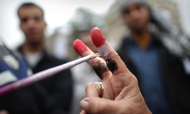 A woman makes a victory sign as her fingers are painted with the colours of the Egyptian flag in Tahrir Square.