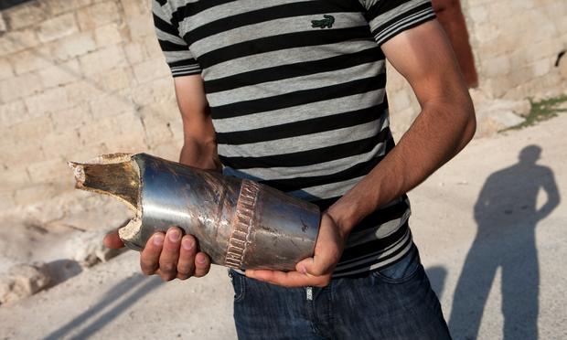 A Syrian citizen holds the remains of a projectile shot by a tank near the town of Khan Sheikhun.