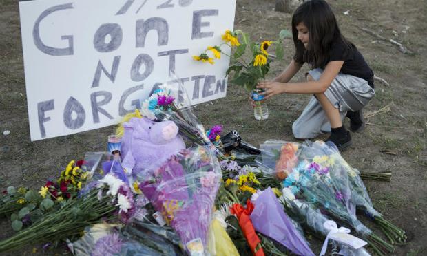 A girl leaves flowers at a memorial near theater where 12 people were killed July 20, 2012 in Aurora, Colorado.