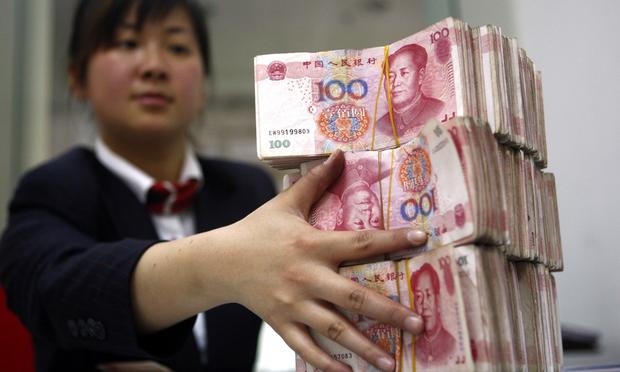 A Chinese bank worker arranges stacks of 100-yuan notes.