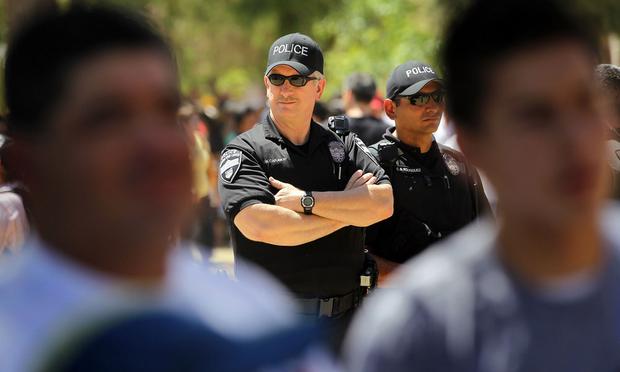 Police watch as opponents of Arizona's new immigration enforcement law gather outside the state capitol building.