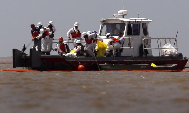 Oil spill cleanup workers adjust an oil boom at South Pass near the mouth of the Mississippi River on May 14, 2010 near Venice, Louisiana.