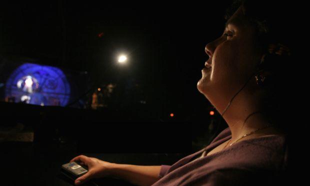 A blind theater-goer uses D-Scriptive, a technology that provides in the moments descriptions of the stage action. Courtesy of Sound Associates