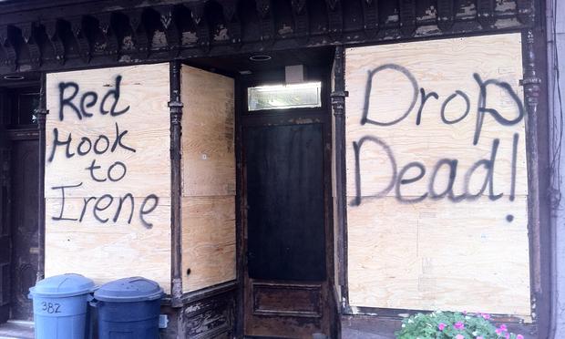 Across Van Brunt street from the still bustling restaurant, a boarded up shop window reads 'Red Hook to Irene: Drop Dead.'