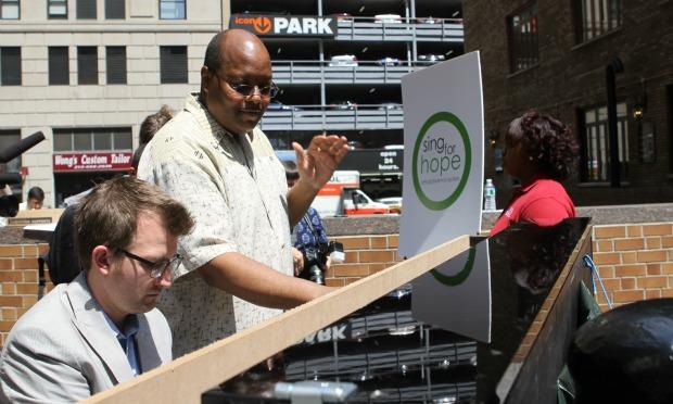 Pianist Brian Neff plays while New York City Housing Authority Youth Chorus director Larry Matthew conducts and turns pages. Pianist Brian Neff plays while New York City Housing Authority Youth Chorus director Larry Matthew conducts and turns pages.